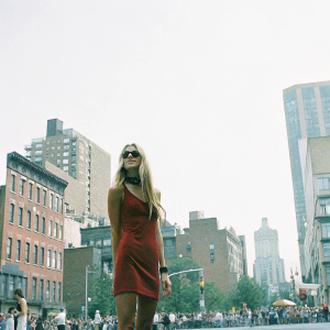 Jessica Hart, Caucasian model, long blonde hair, red dress, black choker. Street style photo, urban backdrop.