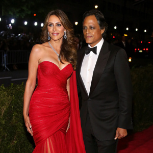 Elizabeth Hurley and Arun Nayar at the Met Gala. Both wear formal gowns and tuxedos. Flashing lights in background.