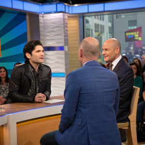 Matt Lauer interviewing Corey Feldman and a bald man in a dark blue suit. Studio audience, colorful background