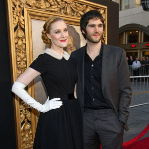 Evan Rachel Wood and Jim Sturgess at the film festival premiere. Evan in a black dress with a white glove, standing in front of a gold-framed, ornate backdrop with intricate designs.