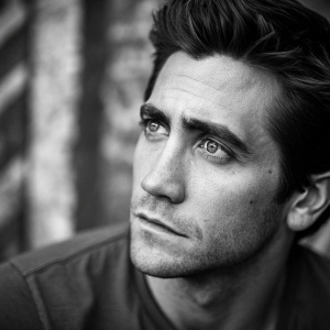 Jake Gyllenhaal, intense gaze, black and white close-up portrait. Abstract blurred background