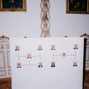 Genealogy chart depicting Donald Trump's family tree. Features flat cartoonish figures and detailed realistic portraits of key figures. Set against an opulent, warm-toned interior with ornate furnishings.