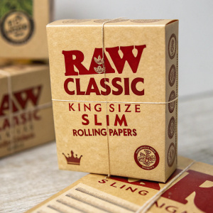A close-up of a cardboard box labeled with the RAW Classic King Size Slim Rolling Papers brand. The box features multiple labels with bold red text.