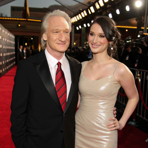 Bill Maher and Cara Santa Maria on the red carpet. Black tuxedo, red striped tie, Cara in a shiny beige dress.