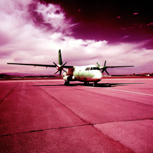 A Guardia Civil Casa CN-235 aircraft, predominantly white with green accents, parked on a tarmac. Light clouds drift across the sky. High-definition photo.