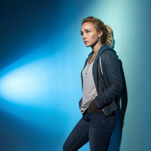 Hayden Panettiere, intense facial expression, standing against a gradient blue backdrop.