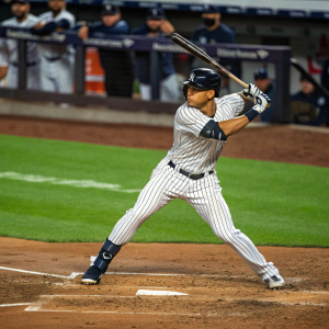 Giancarlo Stanton, MLB star, intense batting stance. The green grass field and distant spectators blurred out. High-action shot