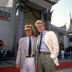 Gary Busey and Jake Busey, dressed in classic 80s attire, including belts and ties, standing outside the Mann's Chinese Theatre in Hollywood for the premiere of 'Big Top Pee-wee'.