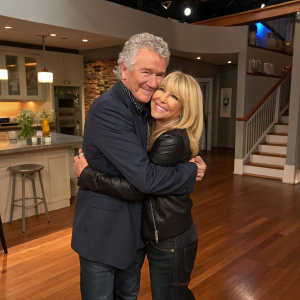 Patrick Duffy and Suzanne Somers embracing at a Step by Step reunion event. Warm, inviting interior with hardwood floors and modern kitchen appliances.