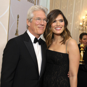 Richard Gere and Mandy Moore posing at the Golden Globe Awards, both dressed in formal attire. Softly lit