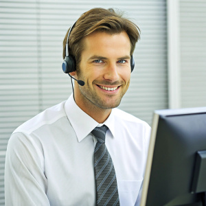 Dedicated male call center operator wearing headset working on computer in call center office.