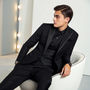 Paulo Dybala, wearing an elegant black suit, poses for a glamorous photo shoot. The background is a sleek, modern studio with soft lighting.