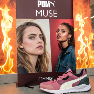 Promotional spread for Puma's Muse Feminist campaign. Two women's faces dominate the design, set against a backdrop with a flame-like texture. Social media icons and a Puma sneaker are featured alongside. Text in Spanish