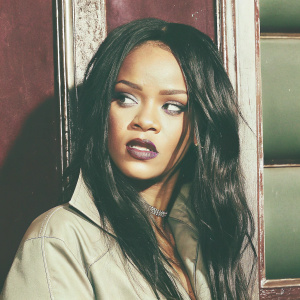 Rihanna's candid shot, dark maroon background. Long dark hair framing her face. Wearing bold lip color. Intense close-up capturing intricate details of her makeup and facial expression.