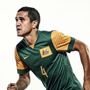 Tim Cahill, Australian footballer, wearing green and gold jersey with Nike logo. Intense expression. White background.