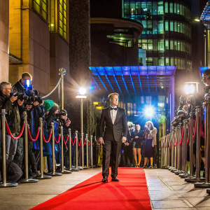 Ben Mendelsohn at the 'Darkest Hour' film festival. He is dressed in a black tuxedo, red carpet, and flashing cameras.