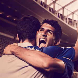 Alvaro Morata and Eden Hazard celebrating a goal. Morata hugs Hazard. Morata's jersey is visible. The stadium background is blurred