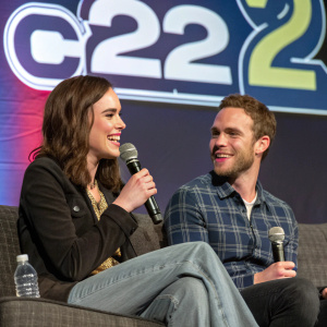 Elizabeth Henstridge and Iain De Caestecker, sitting on a couch. They hold microphones and glasses of water. Behind them, a large C2E2 banner.