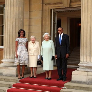Photograph of US President Barack Obama, First Lady Michelle Obama, Queen Elizabeth II, and Prince Philip at a formal gathering. Standing in front of Buckingham Palace's grand entrance adorned with classical columns. Dressed in formal attire.