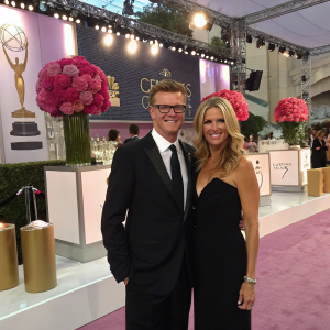 Kevin Reilly and Angela Bromstad at a glitzy awards show. Staging area with branded backdrops, floral arrangements, and refreshment tables.
