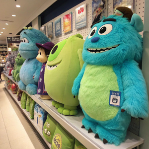 A colorful Monsters Inc. merchandise display. Sulley and Mike Wazowski plush toys lined up on a shelf
