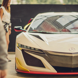 Red Bull-sponsored Acura NSX GT3 in sleek white livery with vibrant red, black, and yellow accents. The car is prominently displayed against a sleek black backdrop, highlighting its aerodynamic design and racing prowess.