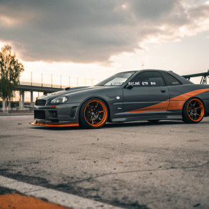Custom Nissan Skyline GTR R34 with a dark gray body and bright orange highlights. Motivational quote on the side panel.