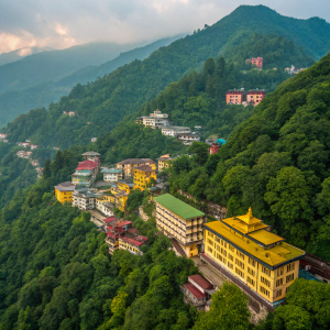 Aerial view of Gangtok, Sikkim. Lush greenery surrounds the cityscape. Buildings of varying architectural styles and vibrant colors, mainly yellow, green, and brown, are closely packed together.