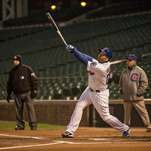 Aramis Ramirez, in a Chicago Cubs jersey, swinging a bat. Solemn scene, devoid of audience, only the umpire and coach visible.
