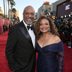 James Pickens Jr and Debbie Allen at the Hollywood premiere. Wearing formal attire, posing with big smiles on the vibrant red carpet.