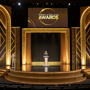 Golden stage with podium and logo backdrop at the Screen Actors Guild Awards. Empty stage, awaiting performers.