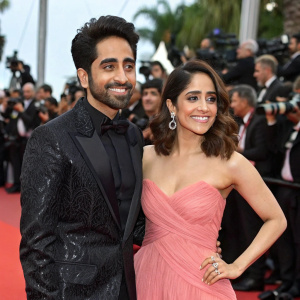 Ayushmann Khurrana and Nushrat Bharucha attend the premiere of a new Bollywood film. Dressed in formal wear, they pose for photographers on a bustling red carpet.