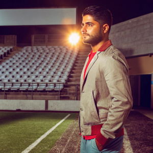 Lorenzo Insigne, intense gaze, standing alone in an empty stadium. Golden evening light casting shadows. Background: dark, silent stands.