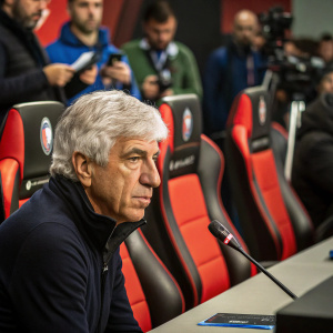 Gian Piero Gasperini, Atalanta BC coach, at press conference. Intense gaze, seated. Red and black chairs, tables, and a microphone in the foreground.