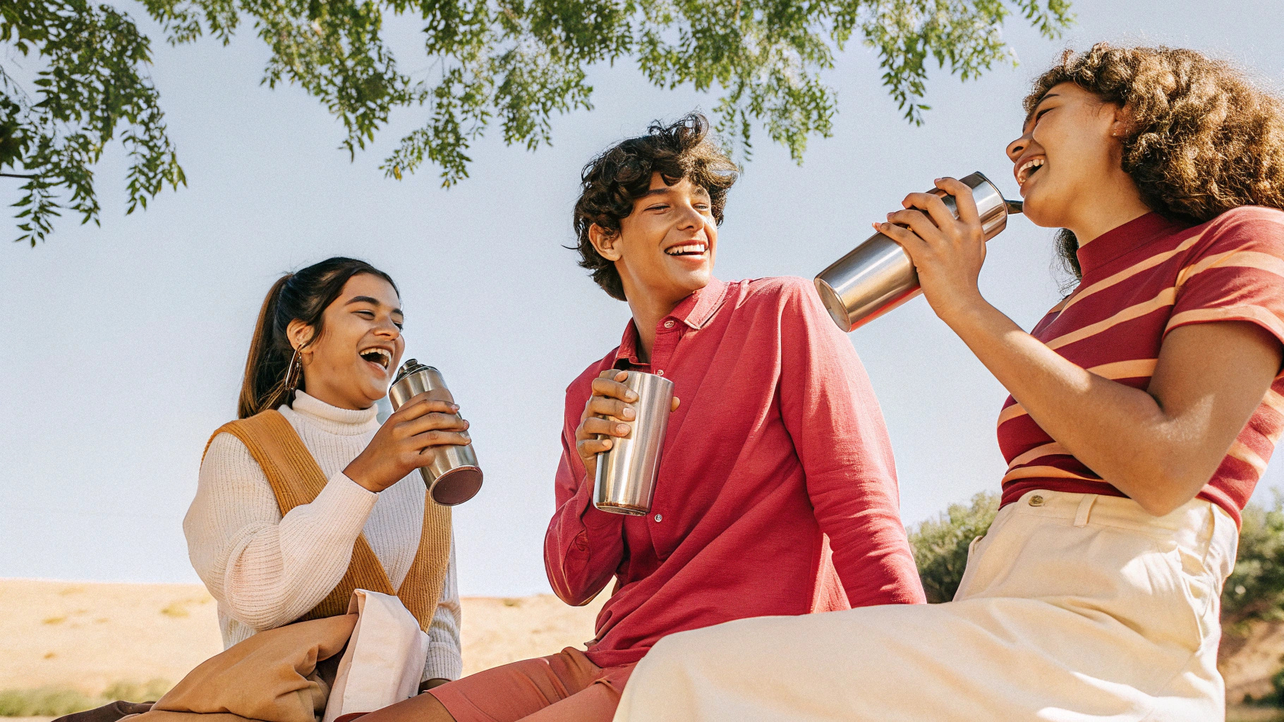 A group of young eco-conscious consumers enjoying beverages from stainless steel bottles during an outdoor activity.