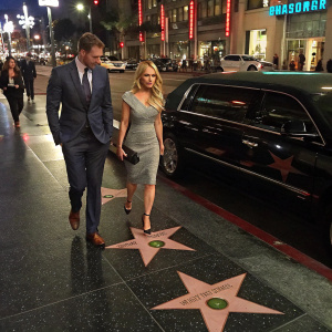 Richard James Sutton and Katie Piper at the Hollywood Walk of Fame. They are walking beside a black limousine.