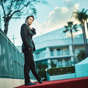 Zach Braff at the Golden Globes. Wearing a sleek black suit, posing for candid photo. Elegant red carpet backdrop.