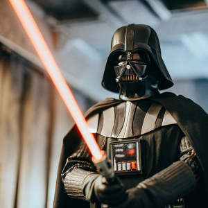 Sideshow Collectibles Darth Vader action figure. Darkened stage with red lightsaber glow. Intimidating stance.