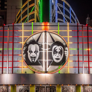 Slipknot band logo, vibrant and colorful, against a neon-lit stage backdrop.