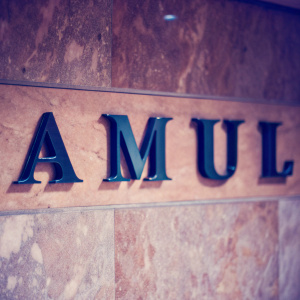 Close-up of sleek, black, modern typography spelling out 'Amul' on a gradient marble wall. Photorealistic image.
