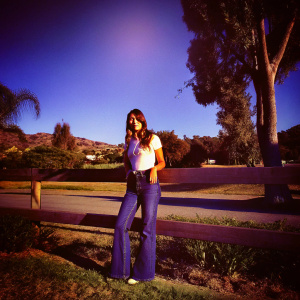 Jessica Alba in a casual outfit, blue jeans, white t-shirt. She's standing in a park, sunny day.