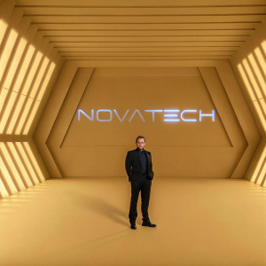 Gian Reyes, CEO, at the launch event for his brand. High-tech, futuristic stage design with large LED screens. Gian stands confidently in the center, wearing a sleek black suit. Name of the brand, 'NovaTech', displayed prominently in bold relief on the backdrop.