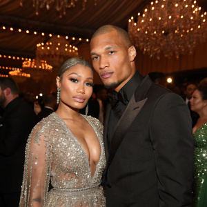 Nicki Minaj and Jeremy Meeks at a star-studded gala. Dressed in elegant gowns and suits. The room is filled with sparkling chandeliers and a sea of blurred faces of celebrities