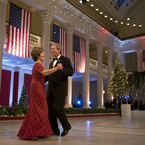 George W. Bush and Laura Bush dancing at the inaugural ball. White House decorated with American flags and festive lights.