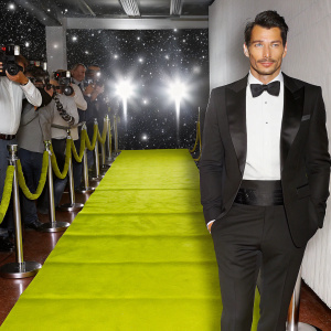 David Gandy at Cannes Film Festival, standing confidently in a black tuxedo. Starlit night, red carpet, flashing cameras.