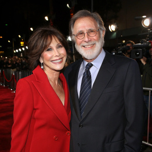 Michele Lee and Fred Rappoport at the Hollywood premiere of 'Gia', both smiling. Michele in red blazer, Fred in dark suit and tie.