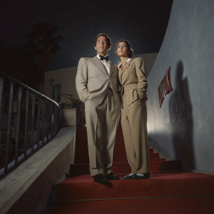 Paolo Sorrentino and Daniela D'Antonio, dressed in formal attire, posing on a red carpet at a Netflix premiere in Naples, Italy. Dark backdrop with a prominent Netflix logo