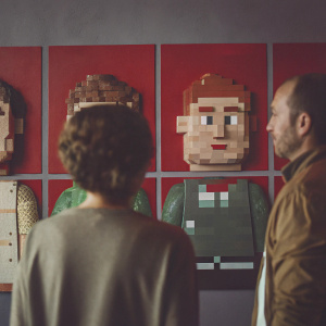 A gallery of pixelated characters in Minecraft style. Each character has distinct features, such as gender, hairstyle, and clothing. Consistent blocky pixel art design. Set against a solid red backdrop.