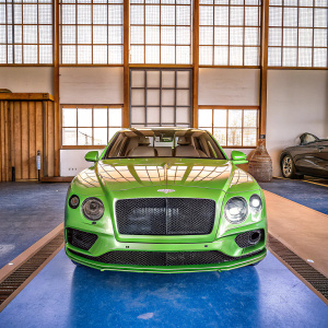 The gleaming Bentley Bentayga S chariot stands majestic in a grand hall. Its front grille and identification plate shine brilliantly. The showroom, a haven of simplicity, bathed in soft natural light filtering through expansive glass windows.
