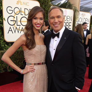 Kelsey Chow and Neil Lane, glowing with joy, at the Golden Globe Awards. Kelsey in a shimmering gown with a waist belt. Neil in a classic black tuxedo.